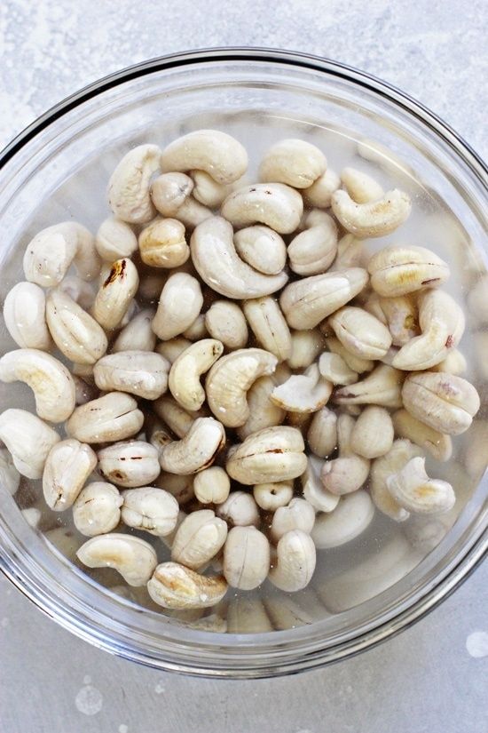 Blötlagda cashewnötter i en glasskål med vatten
